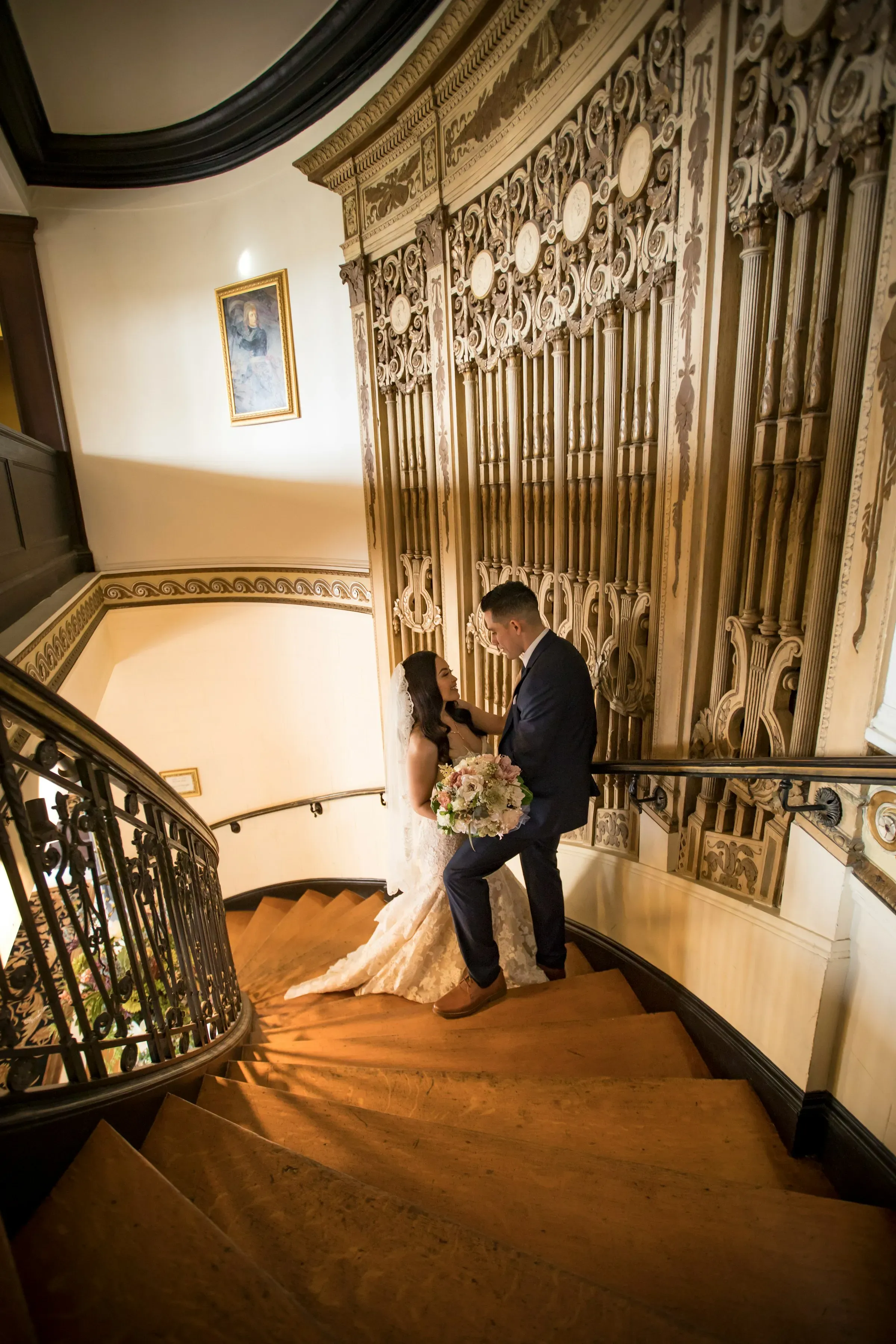 Bride and groom sitting together on stone steps outside a historic building.