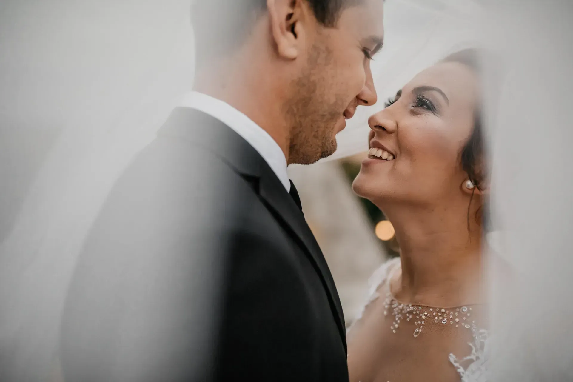 A couple photographed against a plain wall in north light.